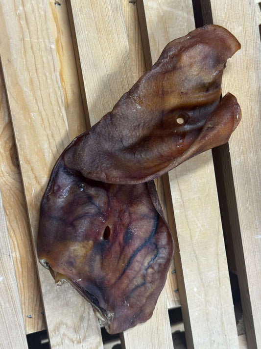 Brown ear-shaped pig ears on a wooden surface