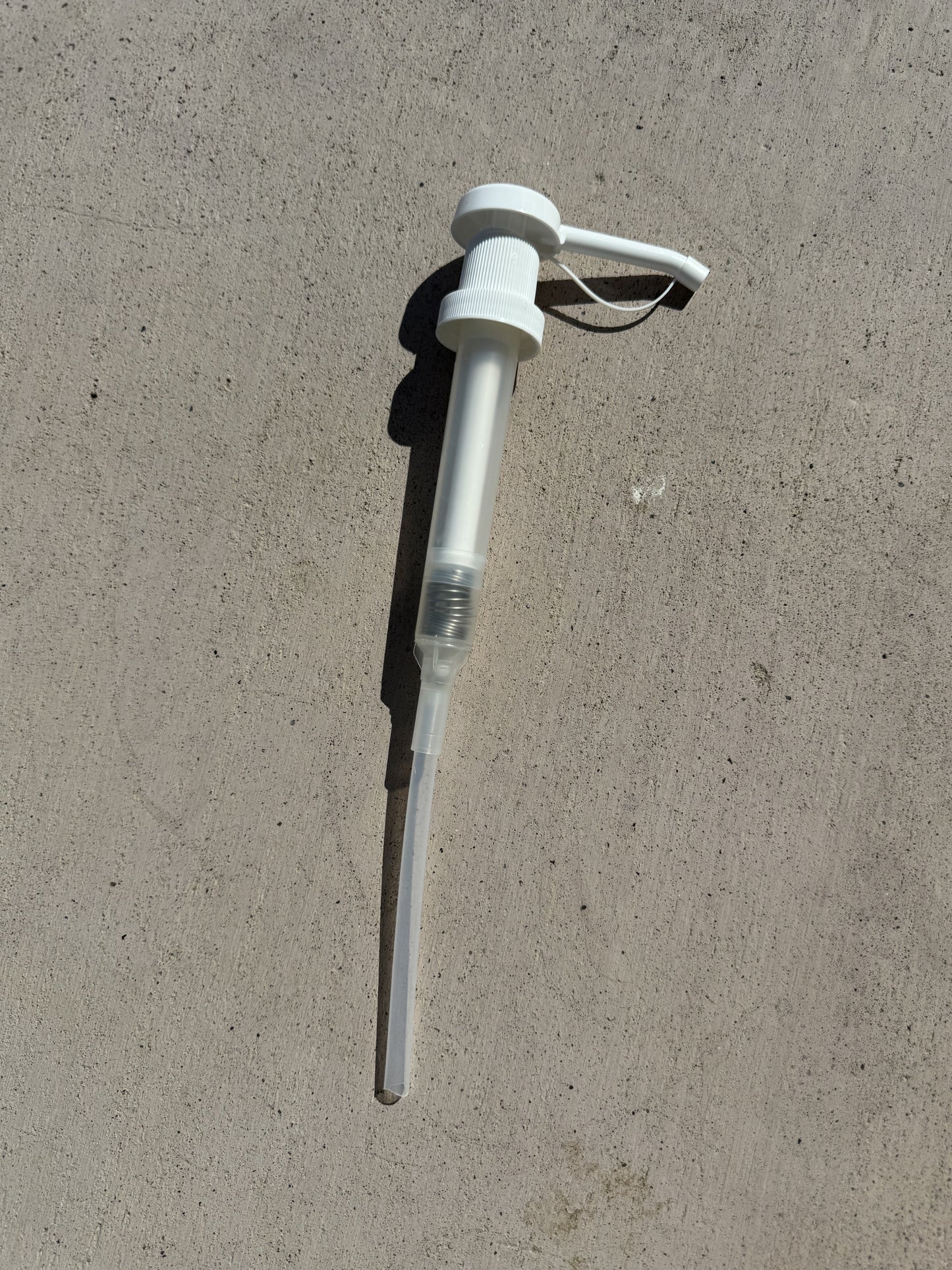 Gallon Pump for Dog Shampoo laying  on gray cement  