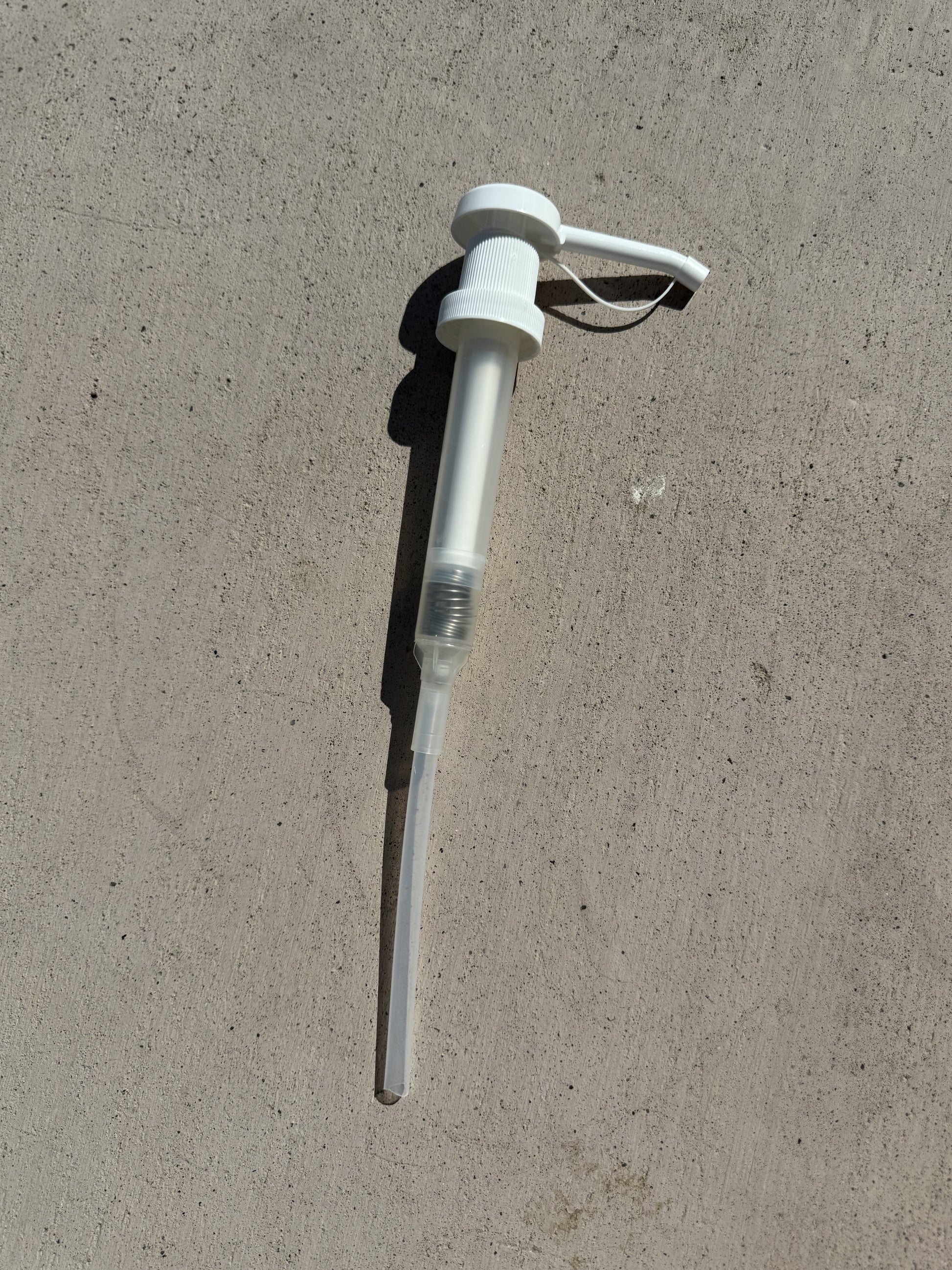 Gallon Pump for Dog Shampoo laying  on gray cement  